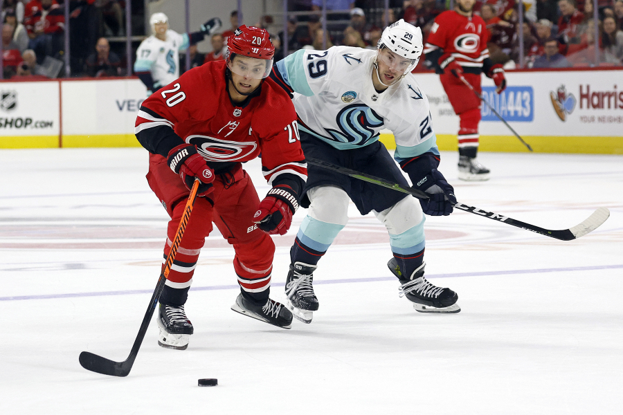 Carolina Hurricanes' Sebastian Aho (20) gathers in the puck on a breakaway as Seattle Kraken's Vince Dunn (29) gives chase during the second period of an NHL hockey game in Raleigh, N.C., Thursday, Oct. 26, 2023.