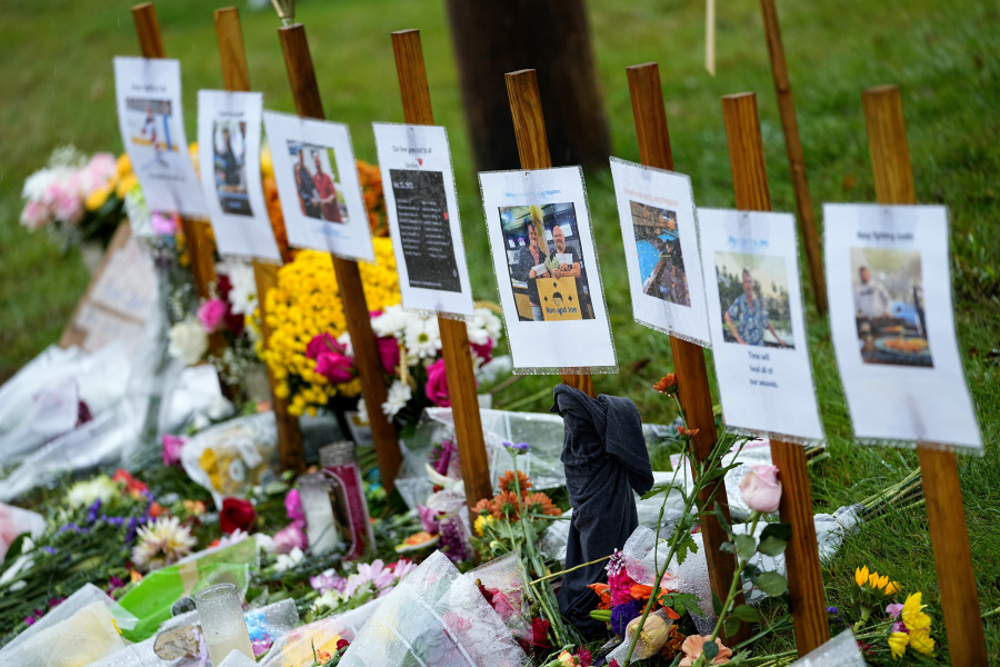 Rain soaked memorials for those who died sit along the roadside by Schemengees Bar & Grille, Monday, Oct. 30, 2023, in Lewiston, Maine. Investigators are still searching for a motive for the massacre that claimed 18 lives as the community seeks a return to normalcy.