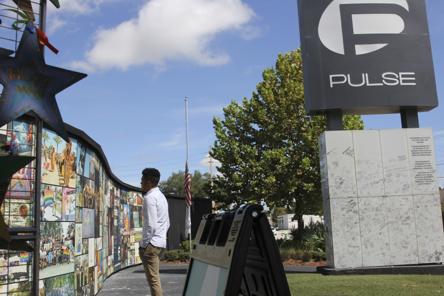 FILE - Brandon Wolf, a survivor of the Pulse nightclub shooting and activist, looks at the photos that are a part of the Pulse memorial in Orlando, Fla., on Sept. 9, 2022. The city of Orlando plans to purchase the gay nightclub property where 49 people were massacred seven years ago, in what at the time was the deadliest mass shooting in modern U.S. history, with the intention of building a memorial for the victims, Mayor Buddy Dyer said Wednesday, Oct. 18, 2023.