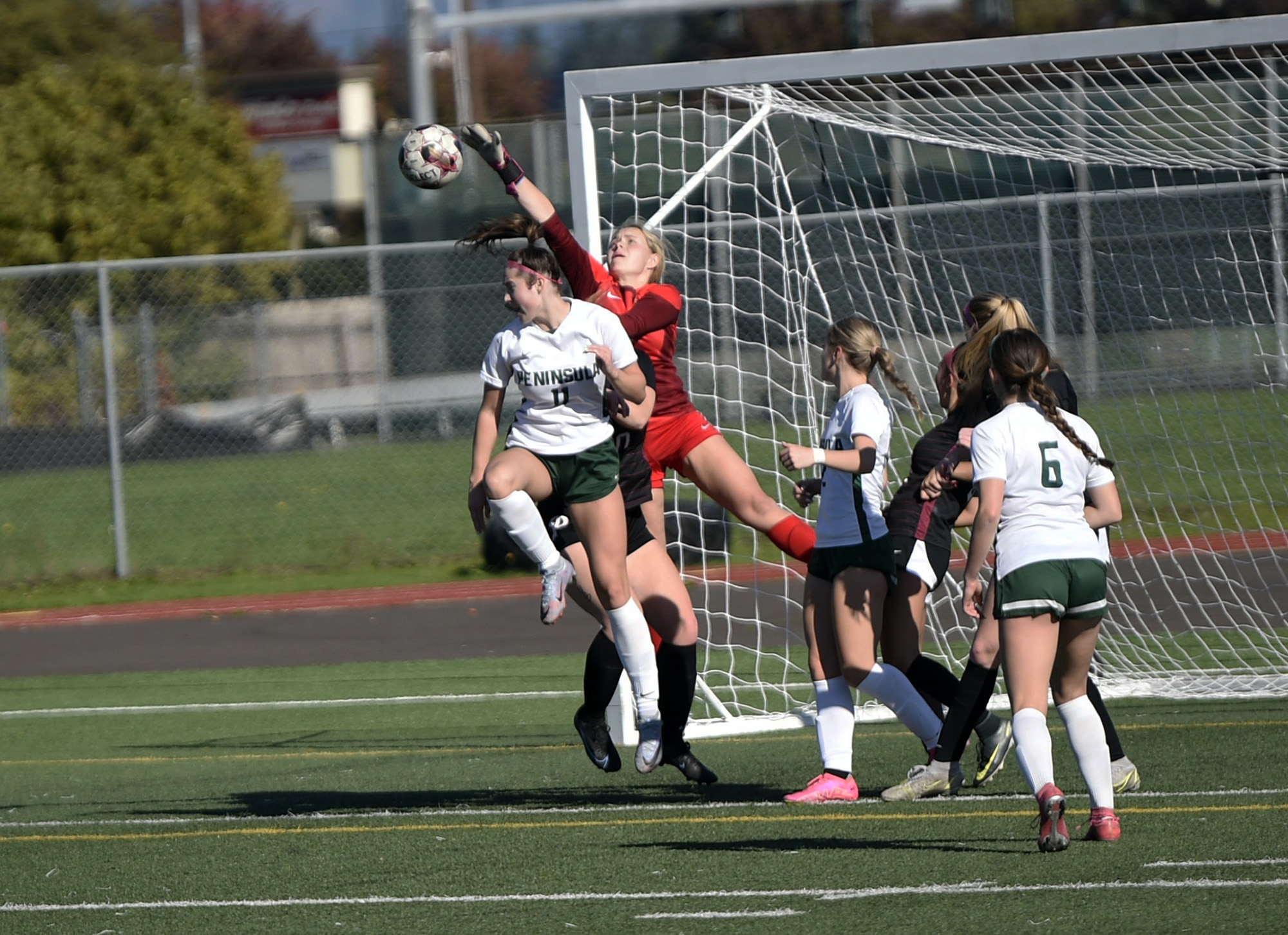 Prairie goalkeeper Lille Amies (in red) knocks the ball away from Peninsula's Makena Getts (11) uring the Falcons' 1-0 loss to Peninsula of Purdy in a Class 3A girls soccer bi-district playoff at Prairie High School on Saturday, Oct. 28, 2023.