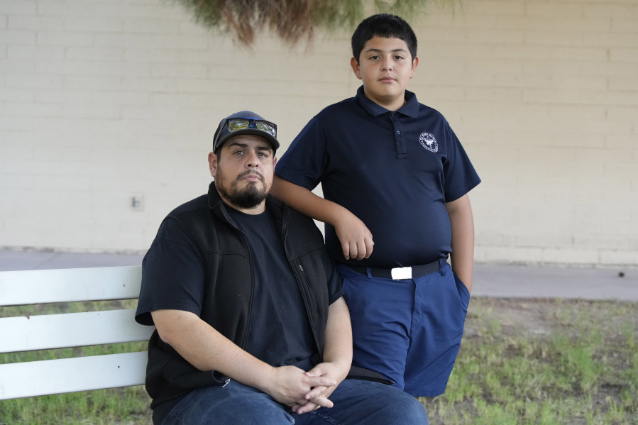 Aaron Galaz and his son pose for a photo on Wednesday, Oct. 18, 2023 in Phoenix. Aaron Galaz said his son is enrolled in a program that uses taxpayer funds to pay for private-school tuition in part so his son could be challenged more in class. At least four states that have made most children eligible for taxpayer-funded scholarships to private schools are seeing more families using the programs than planned. That could cost taxpayers, but it's early to know the exact budget implications.