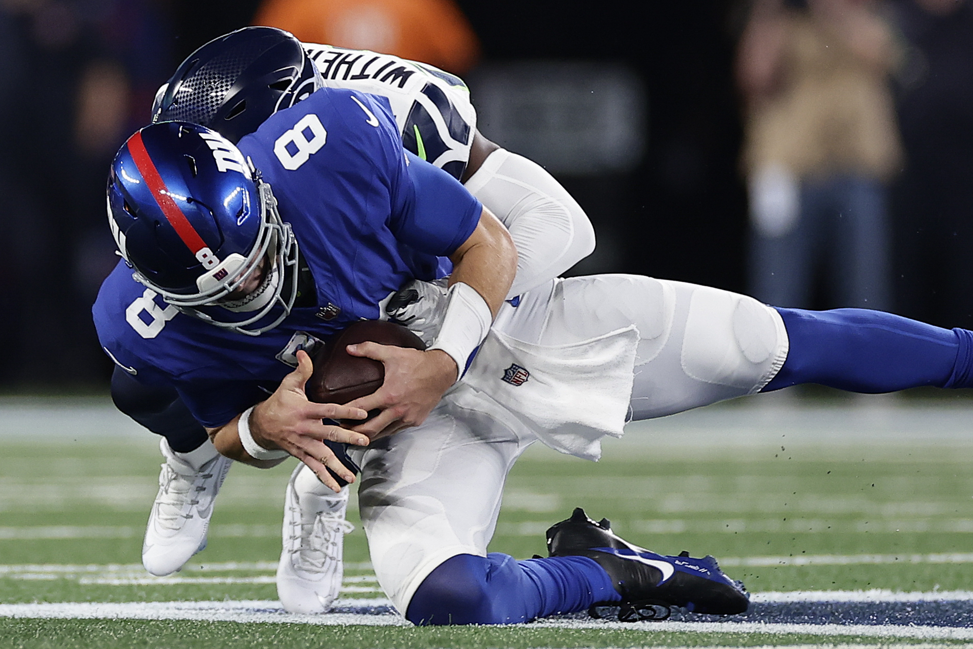 New York Giants quarterback Daniel Jones (8) is sacked by Seattle Seahawks cornerback Devon Witherspoon (21) during the first quarter of an NFL football game, Monday, Oct. 2, 2023, in East Rutherford, N.J.