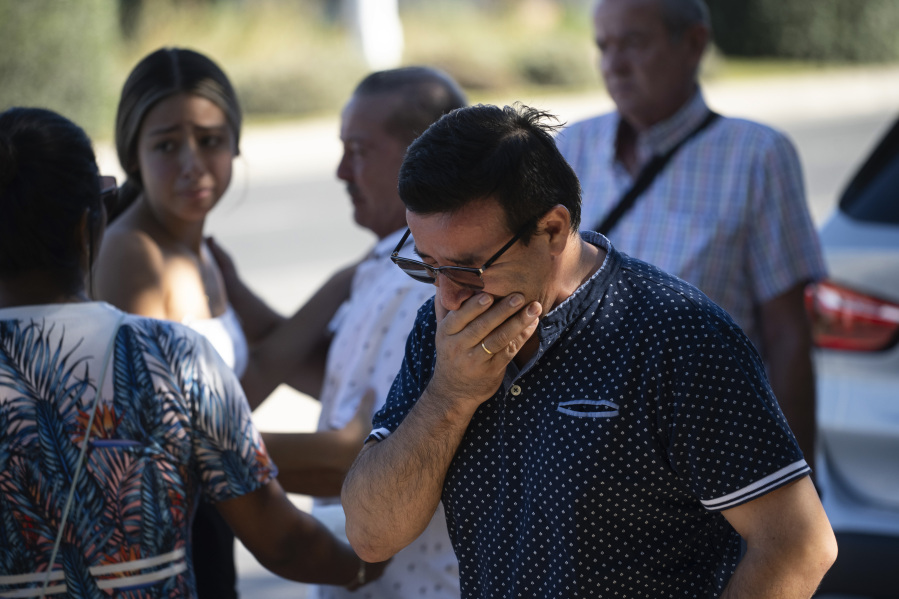 Family members grieve while waiting at a nearby sports palace where a point has been set up to assist relatives after a fire in a nightclub in Murcia, Spain in the early hours of Sunday Oct. 1, 2023.