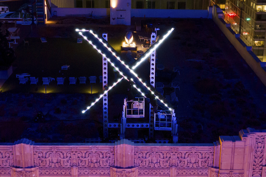 File - Workers install lighting on an "X" sign atop the company headquarters, formerly known as Twitter, in San Francisco, on July 28, 2023. One year ago, Elon Musk began transforming the social media platform into what is now known as X.