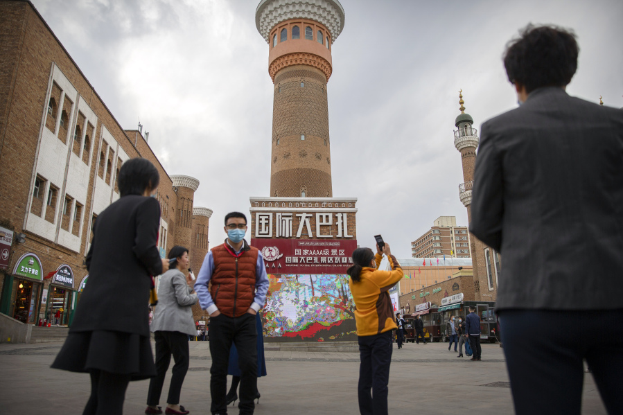 FILE - Tourists take photos near a tower at the International Grand Bazaar in Urumqi in western China's Xinjiang Uyghur Autonomous Region, as seen during a government organized trip for foreign journalists on April 21, 2021. Some U.S. lawmakers are demanding that seafood processed in two Chinese provinces be banned from entering the U.S. market. It's the latest effort by lawmakers to restrict imports of Chinese goods on the grounds of rights abuse, a move that is certain to irk Beijing at a time of tensions over trade and other issues.