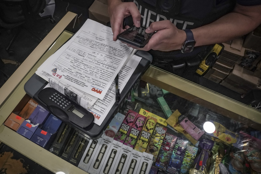 A law enforcement member of New York Sheriff's Joint Compliance Task Force makes a record of confiscated smoking products Sept. 27 during raid of an unlicensed marijuana shop in New York.