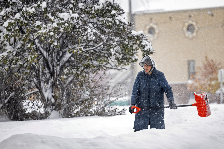 A woman shovel snow, Wednesday, Oct. 25, 2023, in Helena, Mont. The first major snowstorm of the season dropped up to a foot of snow in the Helena area by Wednesday morning, canceling some school bus routes.