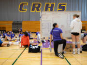 Columbia River High volleyball coach Breanne Smedley talks to senior Evie Wenger while the rest of the team warms up before their practice Oct. 18 inside Columbia River High School&rsquo;s gym. River is the two-time defending Class 2A state champion ahead of the state volleyball state tournament this weekend in Yakima.