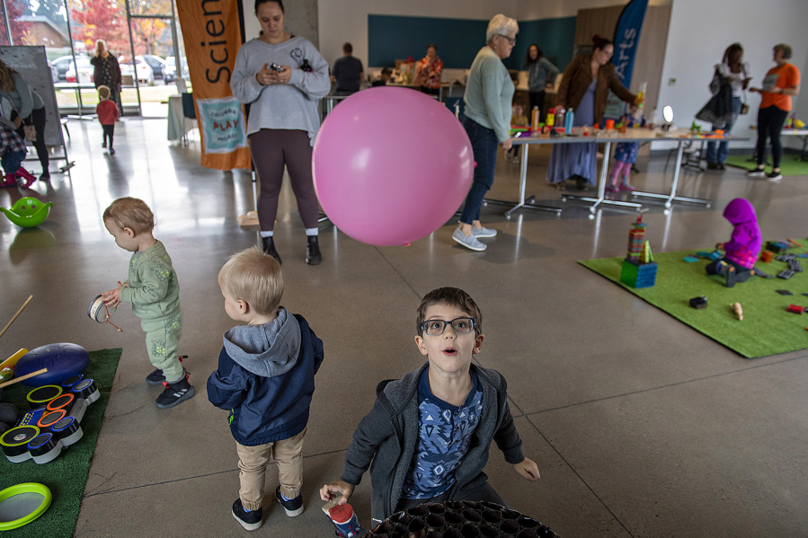 Parker Harris, 4, of Vancouver, center, watches in awe as a balloon takes flight while playing with a wind tunnel at the Fourth Plain Community Commons. The interactive play space is a partnership between Columbia Play Project and Fourth Plain Forward.