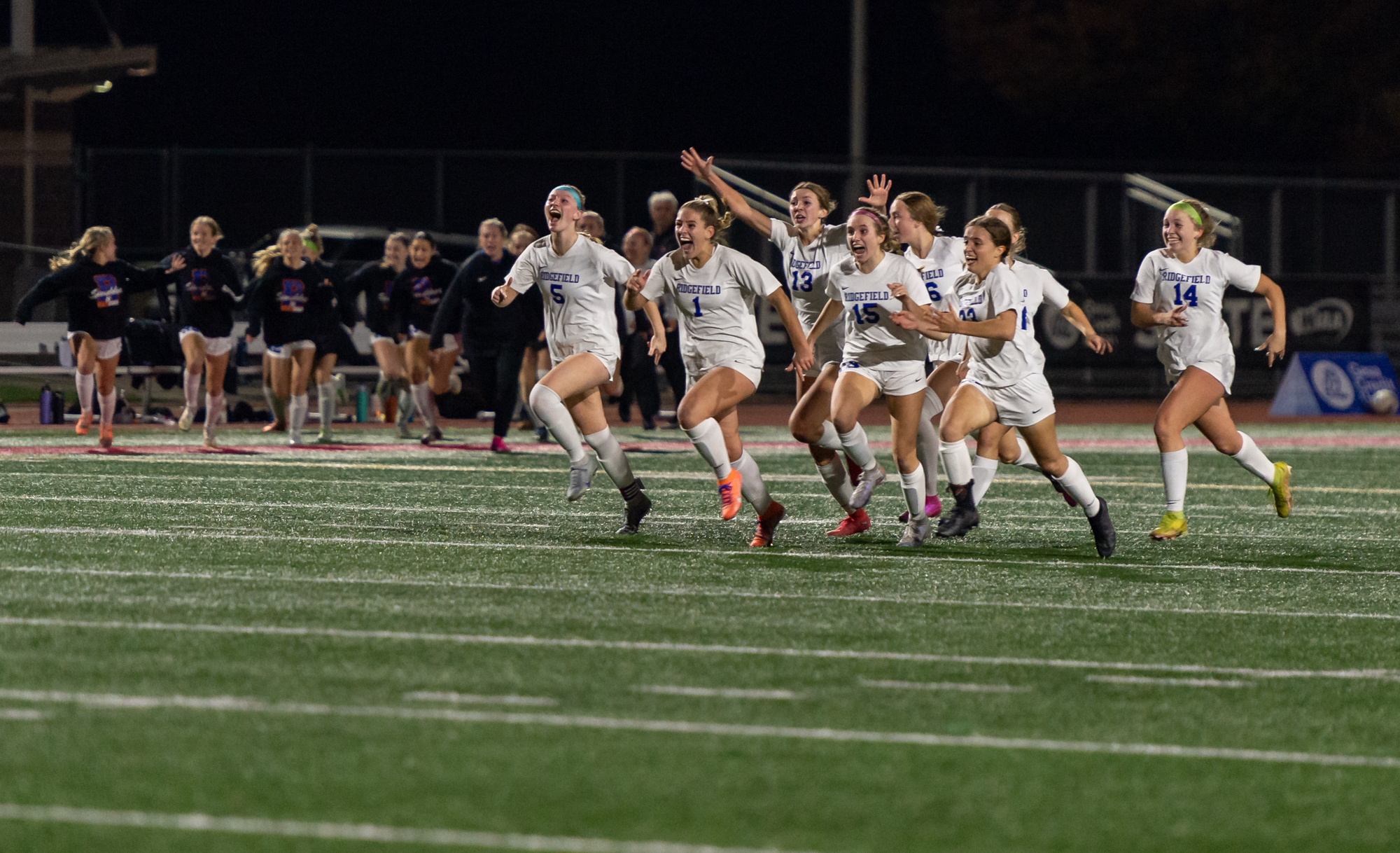 Ridgefield players storm toward their goalkeeper after winning the penalty shootout in the 2A State Girls Soccer Championship on Saturday, Nov. 18, 2023, at Mount Tahoma Stadium in Tacoma.