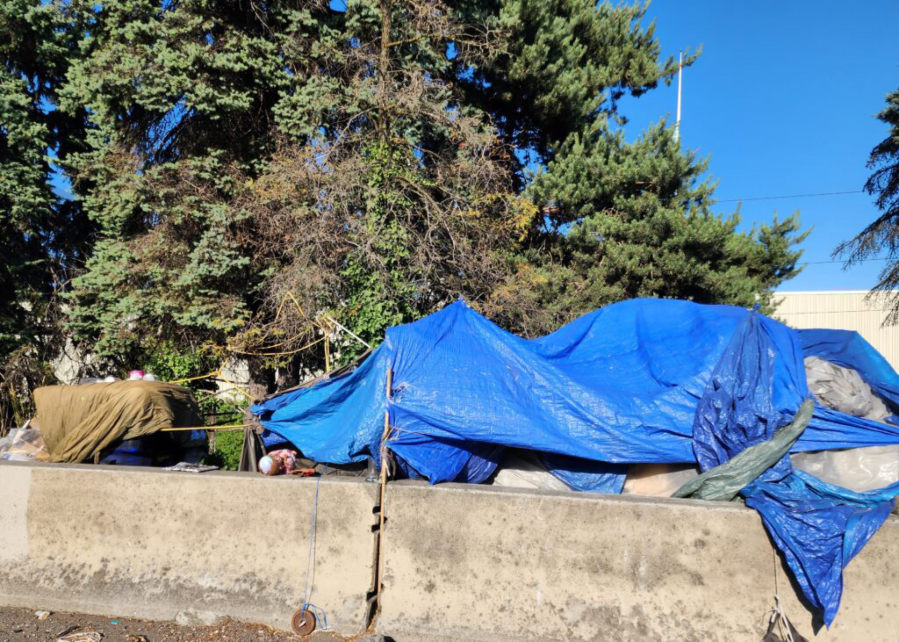 People cover their belongings with tarps next to Interstate 5 in Portland.