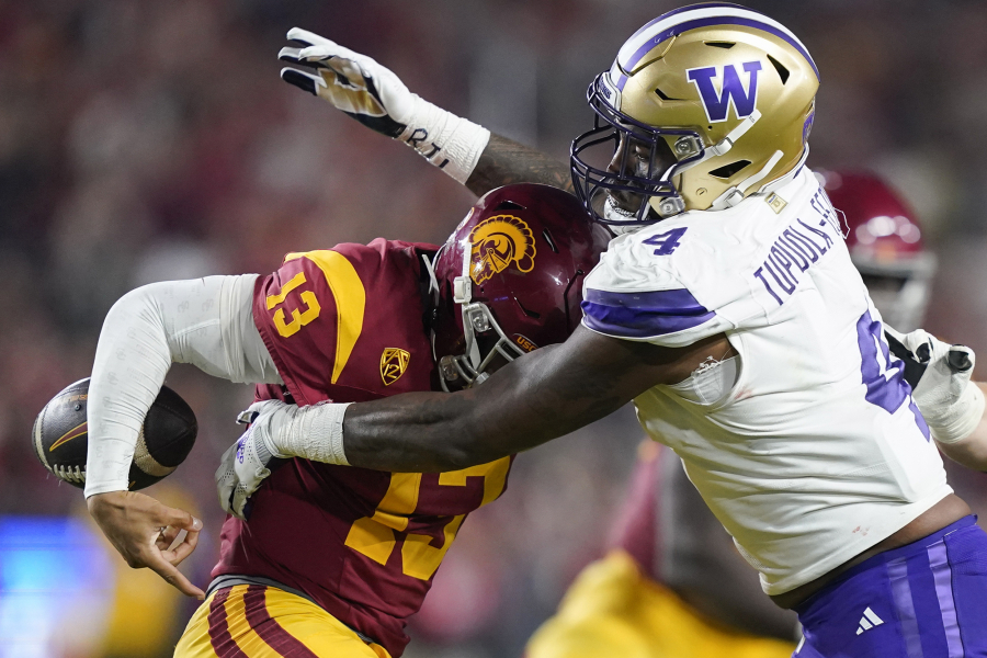 Washington defensive end Zion Tupuola-Fetui, right, forces a fumble by Southern California quarterback Caleb Williams during the first half of an NCAA college football game Saturday, Nov. 4, 2023, in Los Angeles.