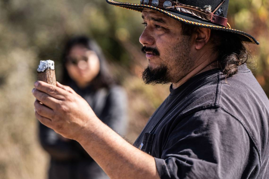Danny Manning, a local firefighter and part of the Native American Maidu community, demonstrates Friday how his ancestors kept fires going by keeping an ember inside a piece of wood during the cultural burn.