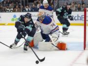 Seattle Kraken center Yanni Gourde (37) reaches for the puck as Edmonton Oilers goaltender Stuart Skinner (74) watches during the first period of an NHL hockey game Saturday, Nov. 11, 2023, in Seattle.
