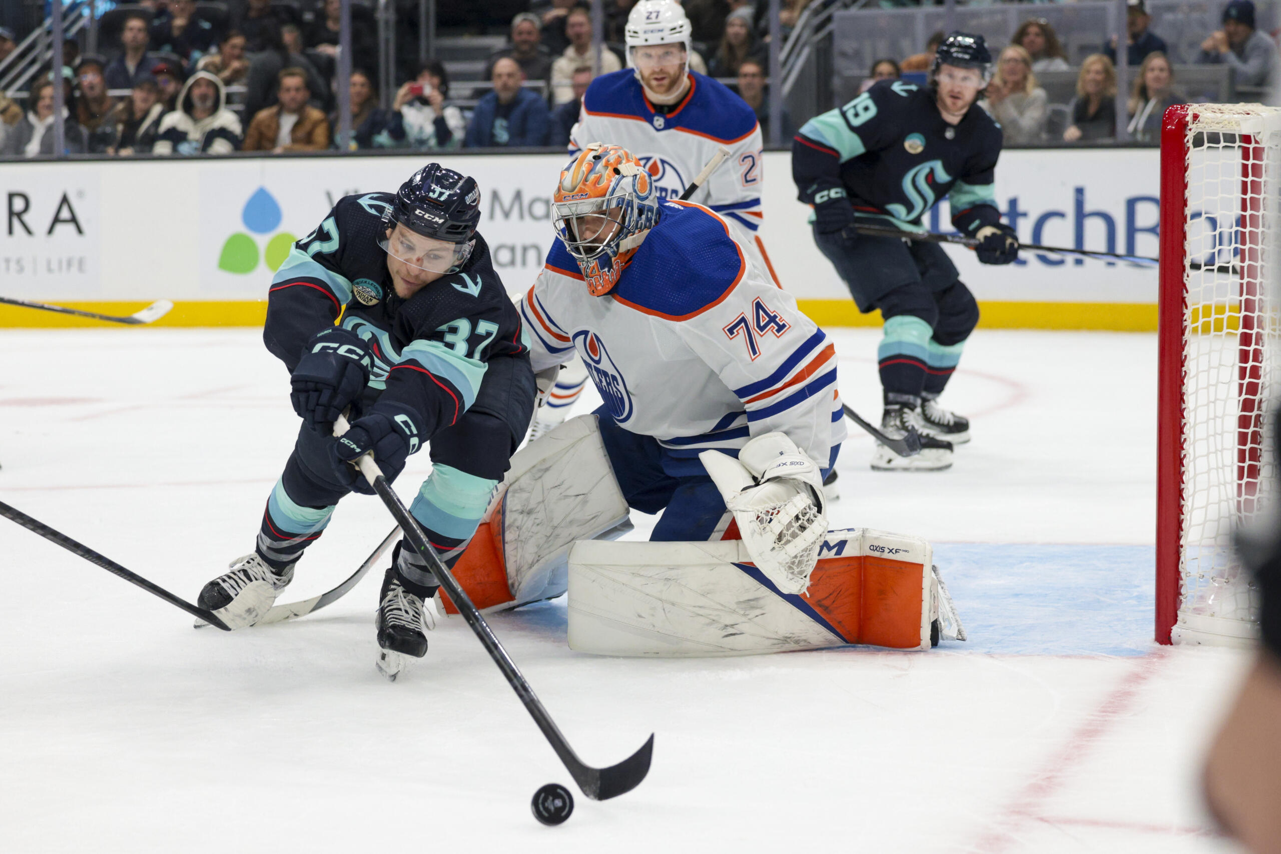 Seattle Kraken center Yanni Gourde (37) reaches for the puck as Edmonton Oilers goaltender Stuart Skinner (74) watches during the first period of an NHL hockey game Saturday, Nov. 11, 2023, in Seattle.