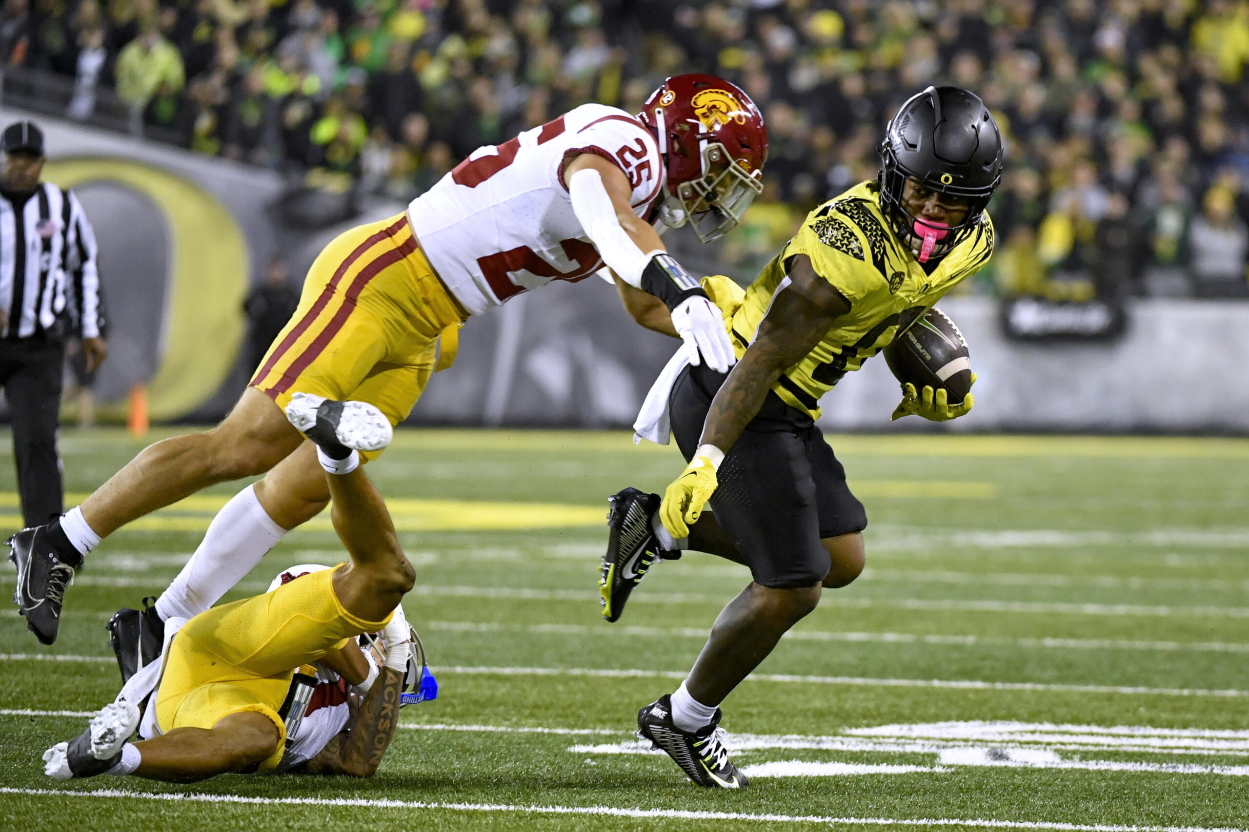 Oregon running back Bucky Irving (0) tries to get away form Southern California linebacker Tackett Curtis (25) during the first half of an NCAA college football game Saturday, Nov. 11, 2023, in Eugene, Ore.