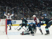 Colorado Avalanche center Ross Colton (20) watches his goal against Seattle Kraken goaltender Joey Daccord (35) as Avalanche right wing Mikko Rantanen, far left, reacts during the second period of an NHL hockey game, Monday, Nov. 13, 2023, in Seattle.