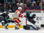 Calgary Flames left wing Andrew Mangiapane (88) scores behind Seattle Kraken goaltender Joey Daccord, right, as defenseman Vince Dunn, left, falls during the third period of an NHL hockey game Monday, Nov. 20, 2023, in Seattle. The Flames won 4-3 in overtime.