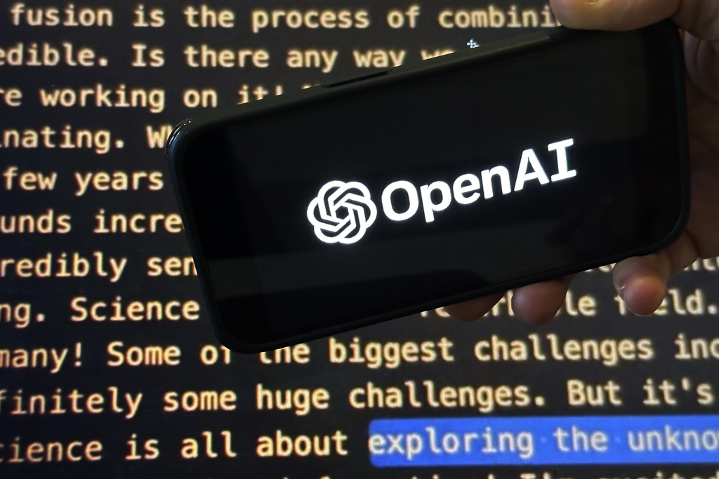 The OpenAI logo appears on a mobile phone in front of a screen showing a portion of the company website in this photo taken on Tuesday, Nov. 21, 2023 in New York.