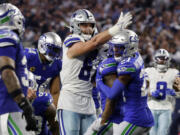 Dallas Cowboys tight end Jake Ferguson (87) signals first down, after catching pass in front of Seattle Seahawks' Quandre Diggs (6) and Devon Witherspoon (21) in the second half of an NFL football game in Arlington, Texas, Thursday, Nov. 30, 2023.