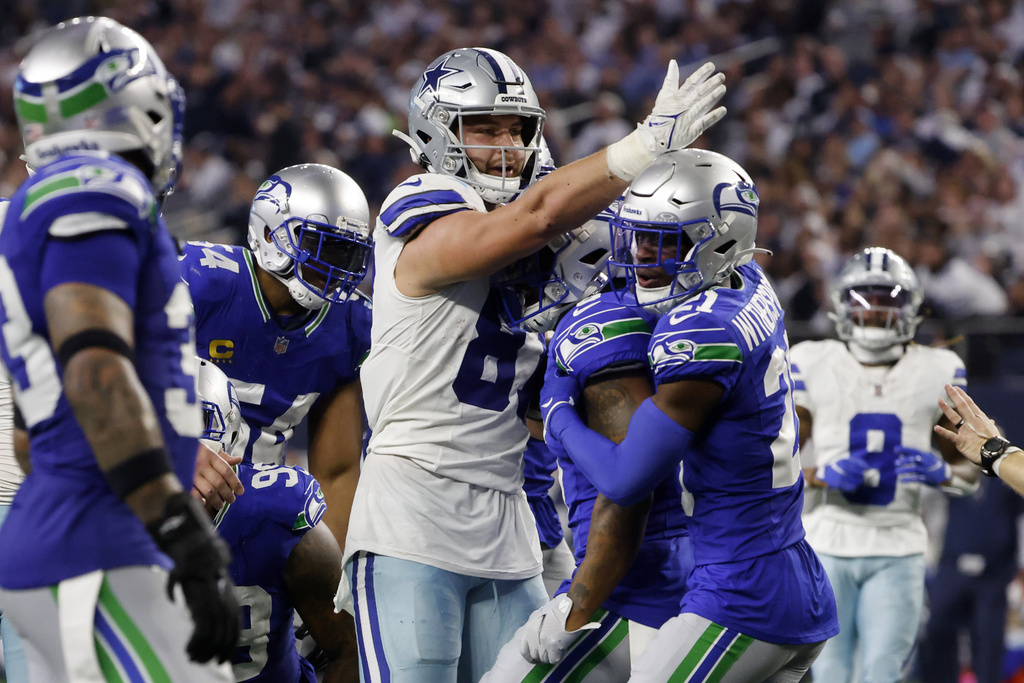 Dallas Cowboys tight end Jake Ferguson (87) signals first down, after catching pass in front of Seattle Seahawks' Quandre Diggs (6) and Devon Witherspoon (21) in the second half of an NFL football game in Arlington, Texas, Thursday, Nov. 30, 2023.
