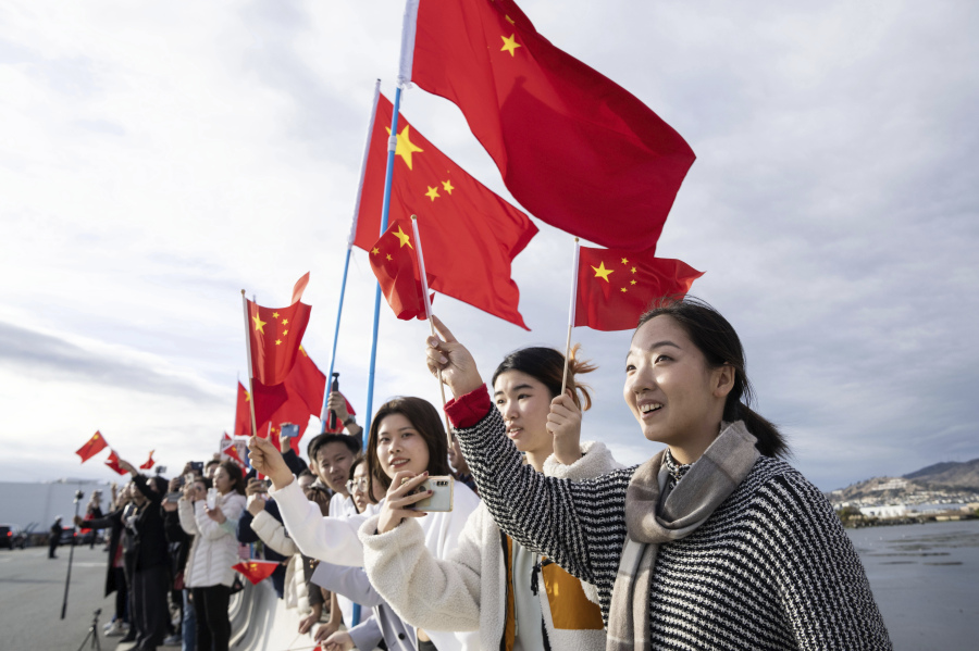 In this photo released by Xinhua News Agency, people wave Chinese flags to welcome Chinese President Xi Jinping in San Francisco, Tuesday, Nov. 14, 2023. Ahead of the highly anticipated meeting on Wednesday between U.S. President Joe Biden and Chinese leader Xi Jinping, Chinese state media have taken a new tone toward the U.S. with less negative coverage, calls for a return to warmer ties and stories of Americans with positive connections to the country.