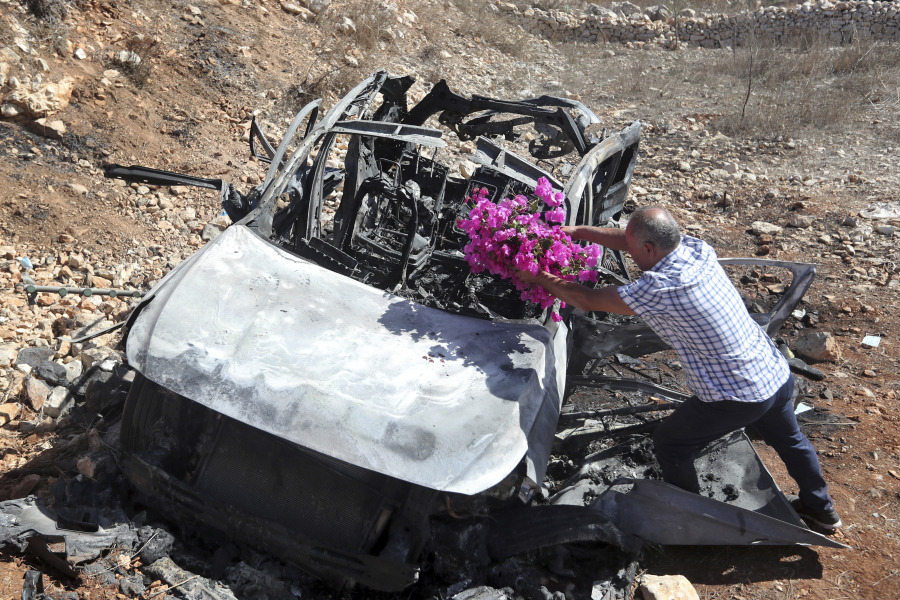 Samir Ayoub, uncle of three children who were killed by an Israeli airstrike, puts flowers on their car in the town of Ainata, a Lebanese border village with Israel in south Lebanon, Monday, Nov. 6, 2023. An Israeli airstrike in south Lebanon on Sunday, Nov. 5, 2023 evening killed four civilians, including a woman and three children, raising the likelihood of a dangerous new escalation in the conflict on the Lebanon-Israel border.