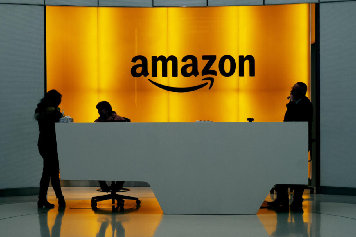 FILE - In this Feb. 14, 2019 file photo, people stand in the lobby for Amazon offices in New York. Amazon finally has its answer to ChatGPT.  The tech giant said Tuesday, Nov. 28, 2023, it will launch Q &ndash; a generative-AI powered chatbot for businesses.