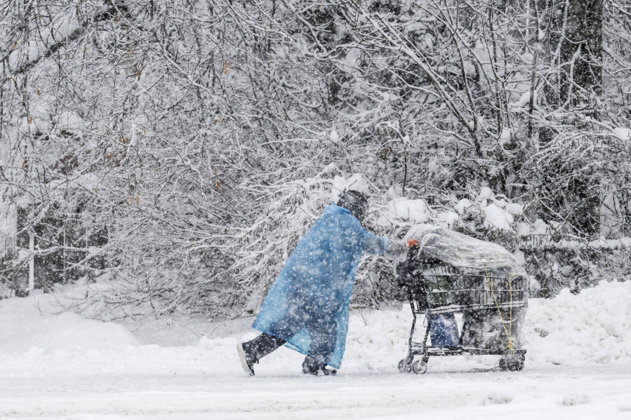 A pedestrian pushes a shopping cart on Cordova Street during a heavy snowfall, Thursday, Nov. 9, 2023 in Anchorage, Alaska. Four homeless people have died in Anchorage in the last week, underscoring the city&rsquo;s ongoing struggle to house a large houseless population at the same time winter weather has returned, with more than 2 feet (0.61 meters) of snow falling within 48 hours.