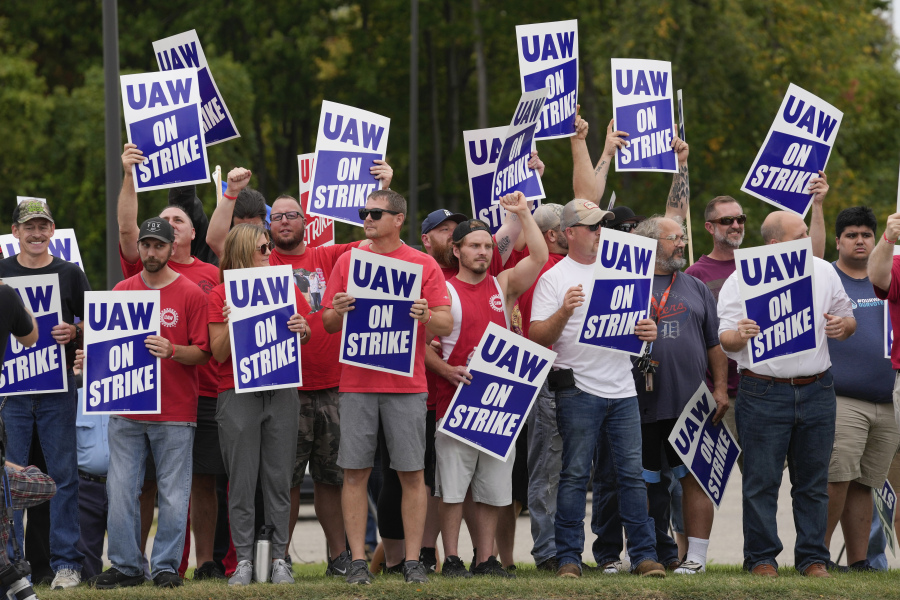 FILE - United Auto Workers members hold picket signs near a General Motors assembly plant in Delta Township, Mich., Sept. 29, 2023. About 46,000 United Auto Workers at GM are expected to wrap up voting on a tentative contract agreement in a close race that will decide the fate of the deal that ended a six-week strike.  The union is expected to announce GM results Thursday evening.