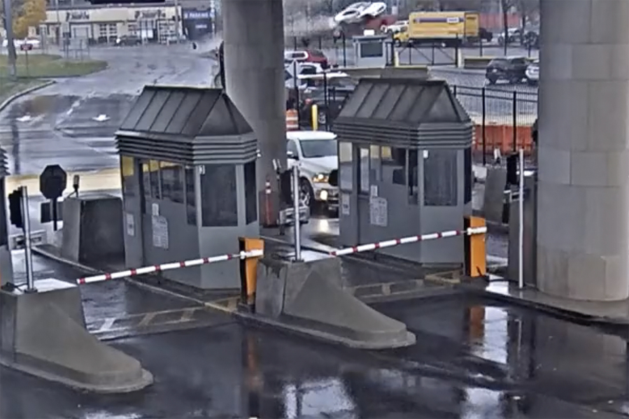 In this image taken from security video, a light colored vehicle, top center, flies over a fence into the Rainbow Bridge customs plaza, Wednesday, Nov. 22, 2023, in Niagara Falls, N.Y. A vehicle exploded at a checkpoint on the American side of a U.S.-Canada bridge in Niagara Falls Wednesday, leaving two people dead and prompting the closing of four border crossings in the area, authorities said.