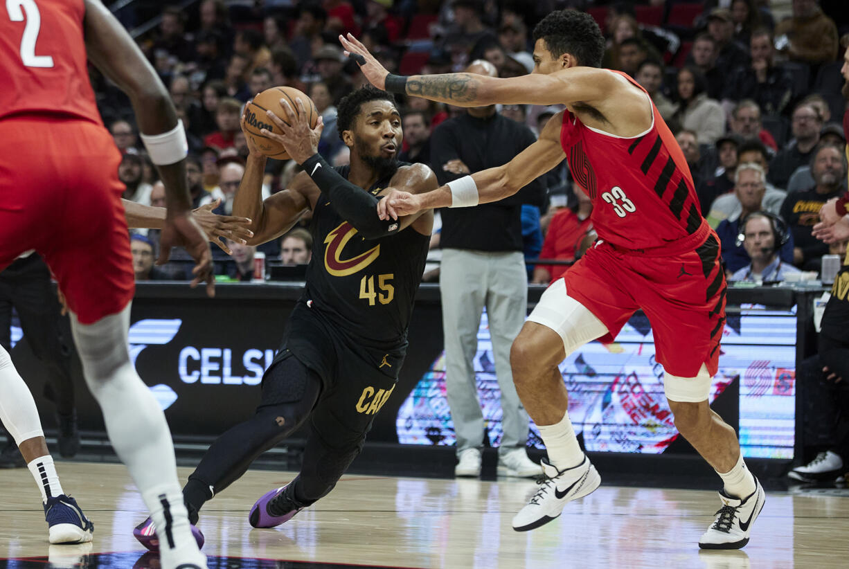 Cleveland Cavaliers guard Donovan Mitchell, left, drives to the basket as Portland Trail Blazers forward Toumani Camara defends during the first half of an NBA basketball game in Portland, Ore., Wednesday, Nov. 15, 2023.