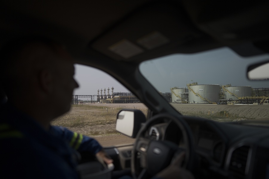 A worker drives by crude oil tanks at Cenovus&rsquo; Sunrise oil facility northeast of Fort McMurray on Thursday, Aug. 31, 2023. Wildfires are bringing fresh scrutiny to Canada&rsquo;s fossil fuel dominance, its environmentally friendly image and the viability of becoming carbon neutral by 2050. (AP Photo/Victor R.