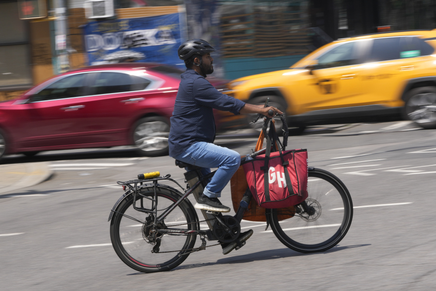 FILE - A delivery worker rides a motorized bicycle, July 25, 2023, in New York. On Monday, Nov. 13, New York City officials said that retailers and food delivery companies must do more to halt the proliferation of unsafe e-bike and e-scooter batteries after a fire blamed on an electric scooter&rsquo;s lithium ion battery killed three people over the weekend.