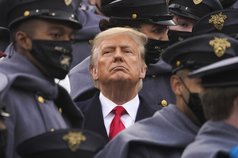 FIlE - Surrounded by Army cadets, President Donald Trump watches the first half of the 121st Army-Navy Football Game in Michie Stadium at the United States Military Academy, Saturday, Dec. 12, 2020, in West Point, N.Y. Experts in constitutional law and the military say the Insurrection Act gives presidents tremendous power with few restraints. Recent statements by former President Donald Trump raise questions about how he might use it if he wins another term.