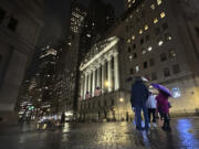 People huddle outside the New York Stock Exchange on Tuesday, Nov. 21, 2023 in New York. World shares were mixed on Wednesday in cautious trading after Wall Street&rsquo;s rally ran out of momentum.