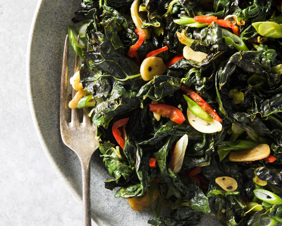 This image released by Milk Street shows a recipe for charred kale with garlic, chilies and lime.
