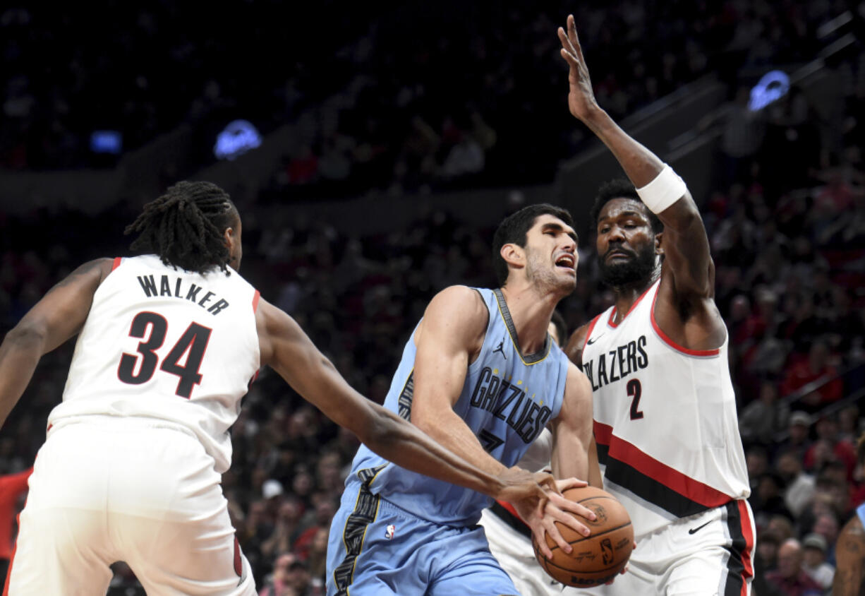 Portland Trail Blazers forward Jabari Walker, left, reaches in as Memphis Grizzlies forward Santi Aldama, center, drives to the basket and Trail Blazers center Deandre Ayton, right, defends during the second half of an NBA basketball game in Portland, Ore., Sunday, Nov. 5, 2023.