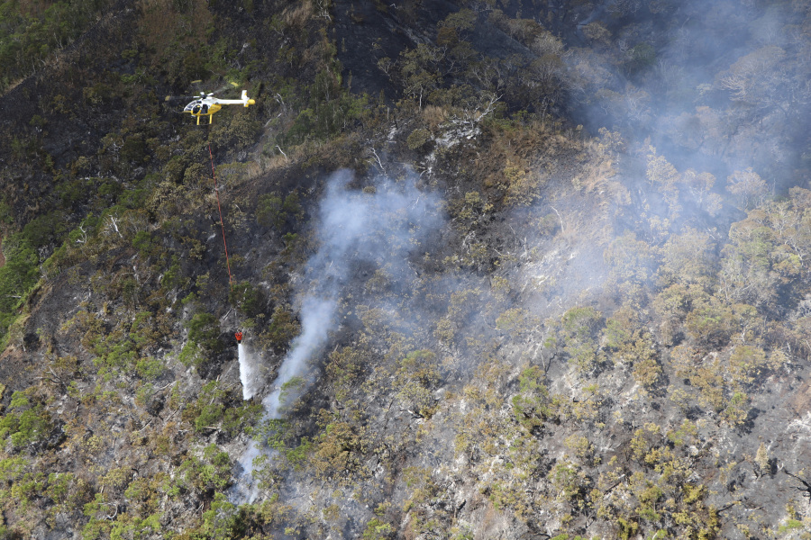 This photo provided by the Hawaii Department of Land and Natural Resources shows a helicopter dropping water on a wildfire burning east of Mililani, Hawaii, on Thursday, Nov. 2, 2023. A wildfire that has burned forestlands in a remote mountainous area of Central Oahu has moved eastward and away from population centers as firefighters continued to battle the blaze.