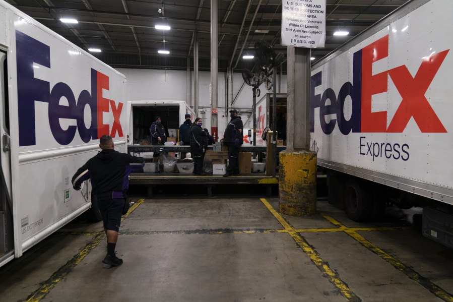 FILE - FedEx delivery trucks are parked next to a conveyor belt while being loaded with packages for delivery at the FedEx regional hub at the Los Angeles International Airport in Los Angeles, Dec. 7, 2021. Carriers like the U.S. Postal Service, FedEx and United Parcel Service have capacity to meet projected demand this holiday season, which is cheery news for shippers and shoppers alike. (AP Photo/Jae C.