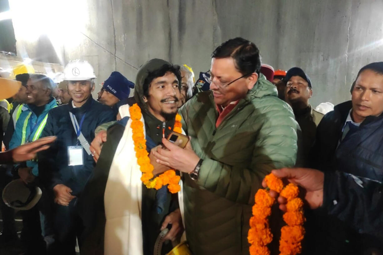 This handout photo provided by the Uttarakhand State Department of Information and Public Relations shows Pushkar Singh Dhami, right, Chief Minister of the state of Uttarakhand, greeting a worker rescued from the site of an under-construction road tunnel that collapsed in Silkyara in the northern Indian state of Uttarakhand, India, Tuesday, Nov. 28, 2023. Dhami said eight workers were rescued so far on Tuesday. The laborers are being pulled out through a passageway made of welded pipes which rescuers previously pushed through dirt and rocks.