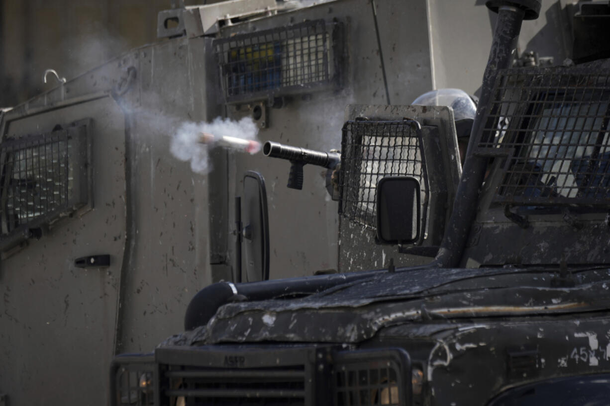 An Israeli officer fires tear gas at Palestinians during a military operation in the Balata refugee camp, West Bank, Tuesday, Nov. 21, 2023.
