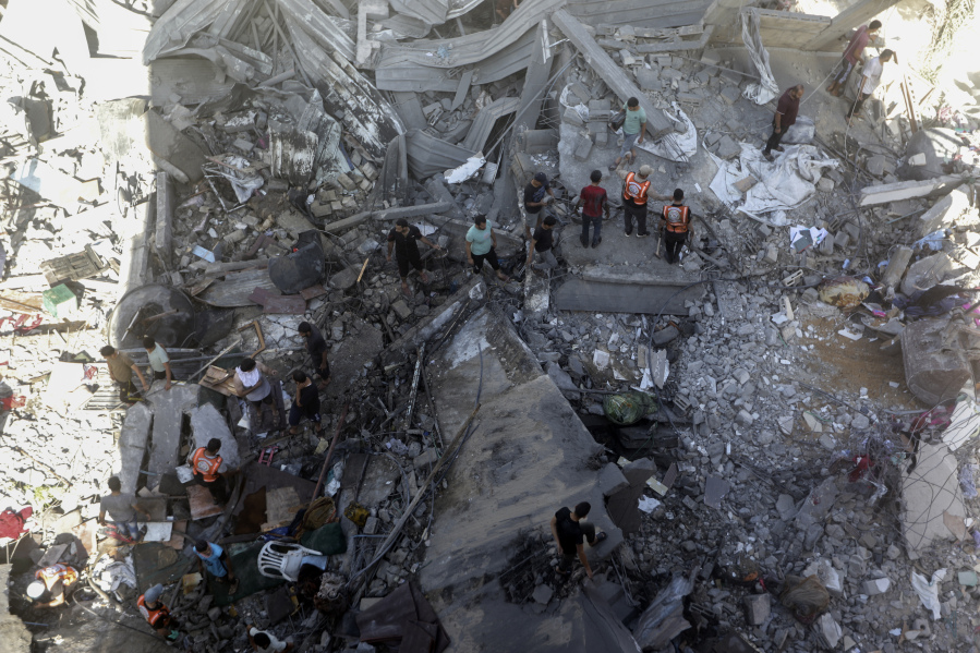 Palestinians look for survivors under the rubble of a destroyed building following an Israeli airstrike in Khan Younis refugee camp, southern Gaza Strip, Monday, Nov. 6, 2023.
