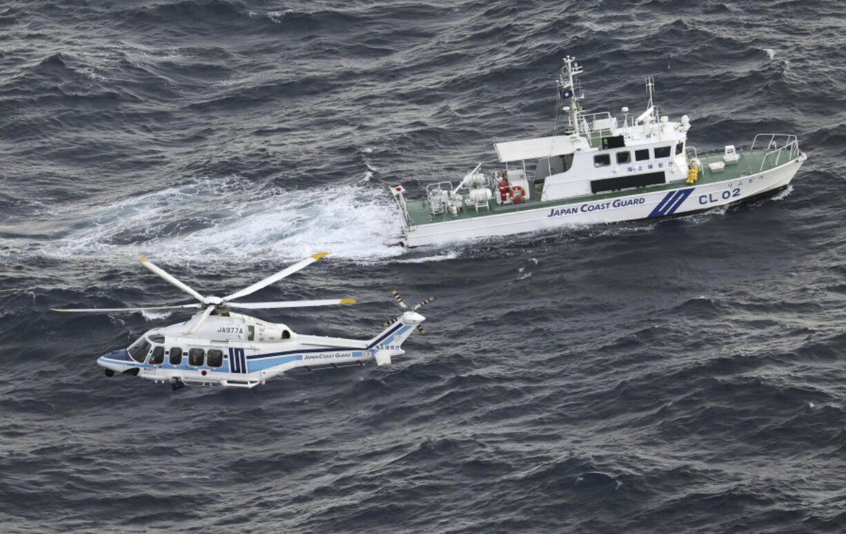 Japanese coast guard helicopter and patrol vessel conduct search and rescue operation in the waters where a U.S. military Osprey aircraft crashed into off the coast of Yakushima Island, Kagoshima prefecture, southern Japan Thursday, Nov. 30, 2023. Japan plans to suspend its own Osprey flights after a U.S. Air Force Osprey based in Japan crashed into waters off the southern coast during a training mission, officials said Thursday.
