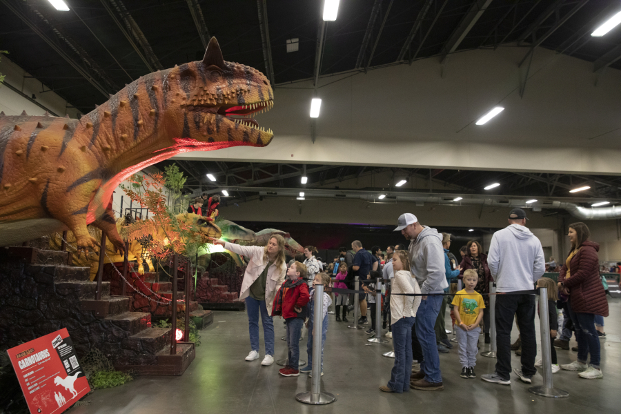 Children wait in line with their families for a chance to ride dinosaurs at Jurassic Quest at the Clark County Events Center in November 2022.