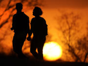 FILE - A couple walks through a park at sunset, March 10, 2021, in Kansas City, Mo. U.S. life expectancy rose in 2022 &mdash; by more than a year &mdash; after plunging two straight years at the beginning of the COVID-19 pandemic, according to a new government report released Wednesday, Nov. 29, 2023. The rise was mainly due to the waning of the pandemic in 2022, researchers said at the Centers for Disease Control and Prevention.