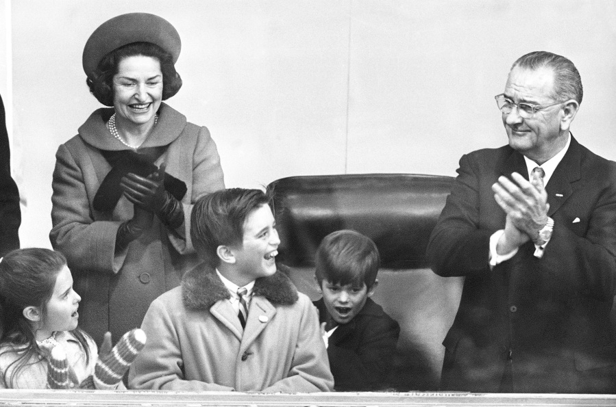 Children of Peace Corps Director R. Sargent Shriver join President Lyndon Johnson and first lady Lady Bird Johnson in the inaugural reviewing stand at the White House during the Jan. 20, 1965, parade. From left are Maria, Robert and Timothy Shriver.