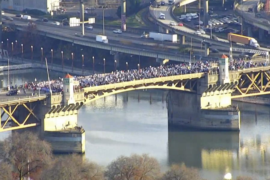 In this KGW-TV image from video, striking teachers march across the Burnside Bridge in Portland, Ore., on Tuesday, Nov. 21, 2023. KGW reported that the Portland Association of Teachers union and their supporters stopped in the middle of the bridge for about 15 minutes. Portland teachers have been on strike since Nov. 1, with class sizes and teacher salaries are among the key issues the union and the school district have been negotiating.