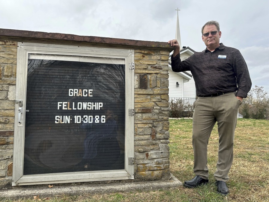 Pastor Kenny Batson stands near a sign displaying the worship service times of Grace Fellowship Church on Nov. 16, 2023, in El Dorado Springs, Mo.   Batson was convicted of a series of crimes in the 1990s but became a Christian pastor after being released from prison. He was pardoned by Missouri Gov. Mike Parson.