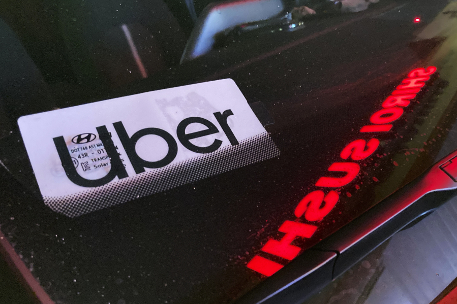 File - An Uber sign is displayed inside a car in Glenview, Ill., on Dec. 17, 2022. Ride-hailing companies Uber and Lyft will pay a combined $328 million to settle wage theft claims in New York, Attorney General Letitia James announced Thursday. (AP Photo/Nam Y.